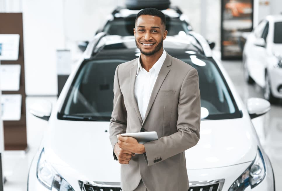 A young South African professional standing confidently in a car showroom — dealership-ready and prepared
